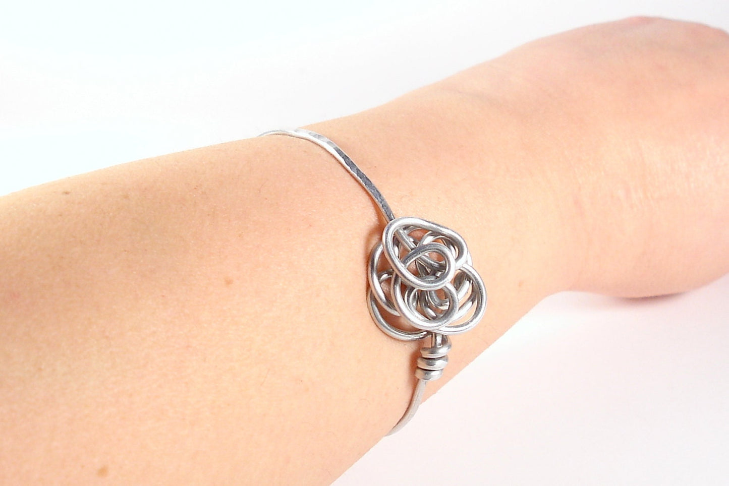 Aluminum wire bracelet with stylized flower. Silver color bangle.